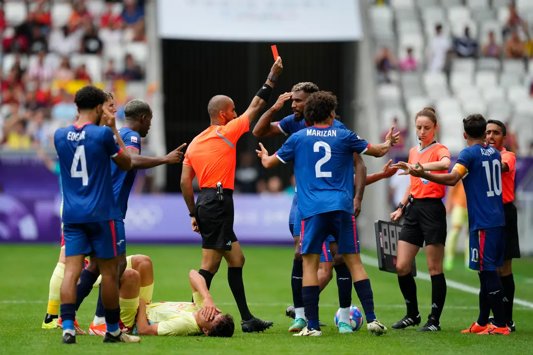 El &aacute;rbitro Adel Al Naqbi (c) le saca la tarjeta roja al dominicano Edison Azcona (d) tras una acci&oacute;n contra Pau Cubars&iacute; (en el suelo) durante el partido del Grupo C de f&uacute;tbol masculino de los Juegos Ol&iacute;mpicos de Par&iacute;s 2024 disputado este s&aacute;bado en el Estadio de Burdeos. EFE/ M. Reino