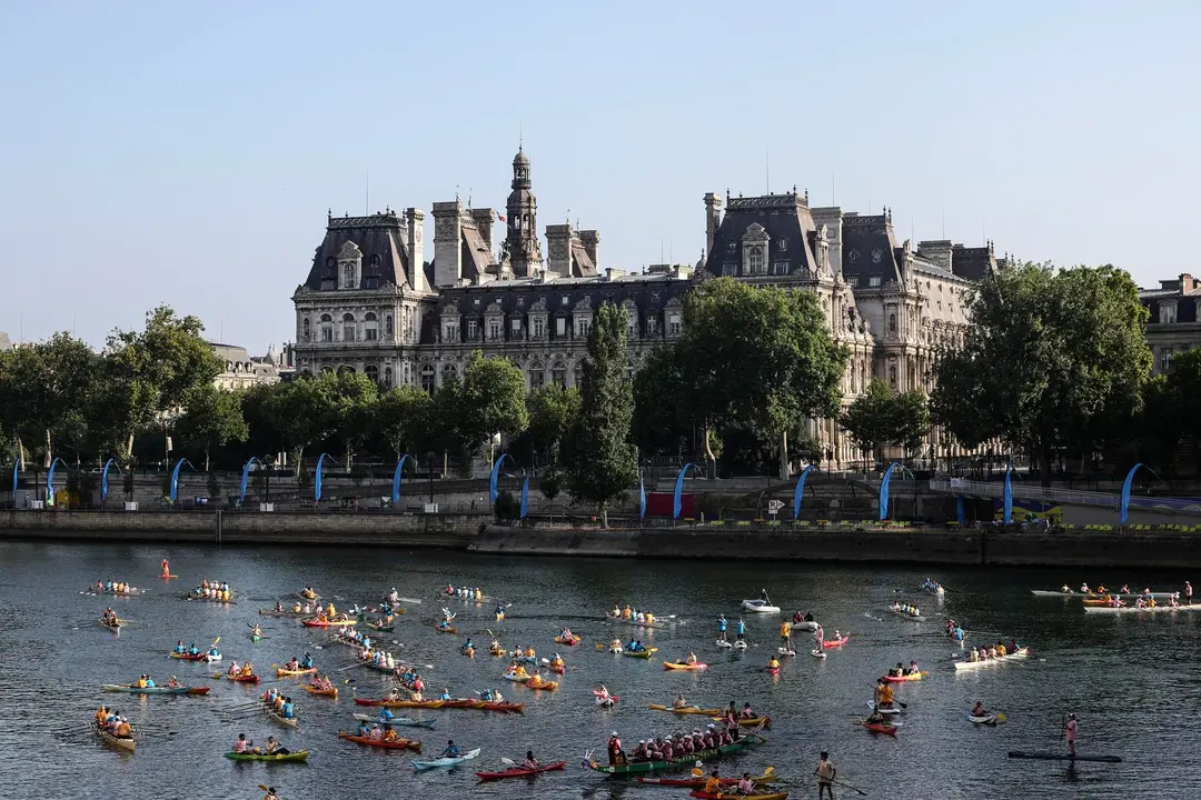 Participantes en el Festival del Sena pasan frente al Ayuntamiento de Par&iacute;s mientras navegan en kayak, reman y practican paddle surf por el r&iacute;o como parte de las celebraciones del primer aniversario de los Juegos Ol&iacute;mpicos de Par&iacute;s 2024. EFE/EPA/TERESA SUAREZ